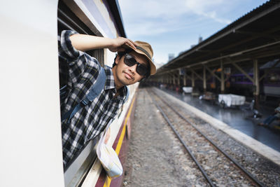 Passenger wearing sunglasses peeking through train window