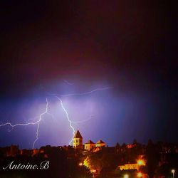 Low angle view of lightning over illuminated buildings at night