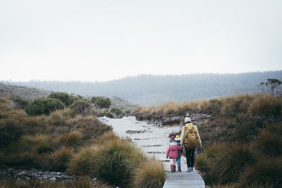 Rear view of mother with children walking on footpath