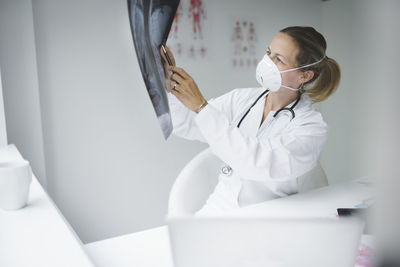 Smiling doctor holding medical x-ray at clinic