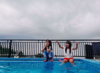 Full length of young woman in swimming pool against sky