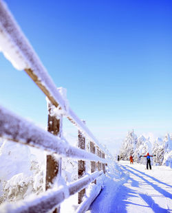 Snow covered railing against blue sky