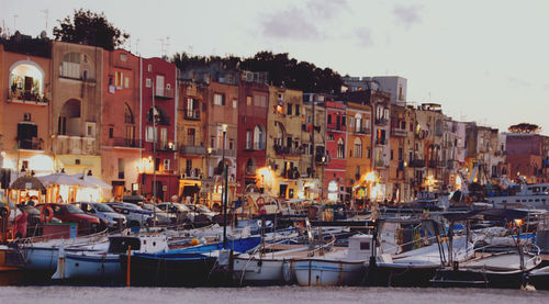 Boats moored at harbor against buildings in city