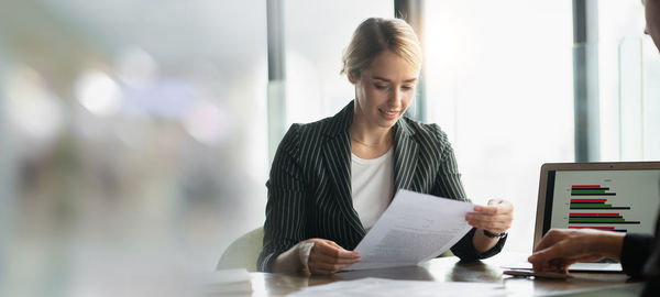 Young woman using mobile phone at table