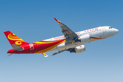 Low angle view of airplane flying against clear blue sky