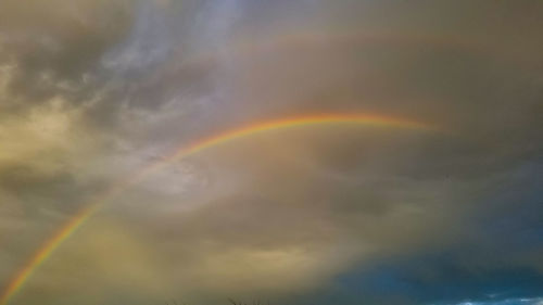 Low angle view of rainbow against cloudy sky
