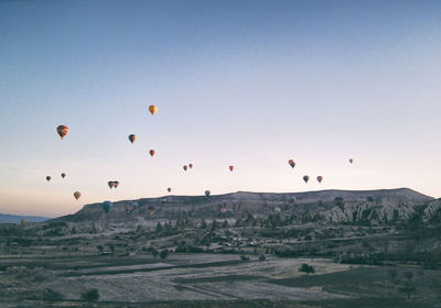 Hot air balloons flying over landscape against clear sky