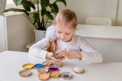 A girl student sits at a desk in the classroom and collects figures / puzzles / small toys 