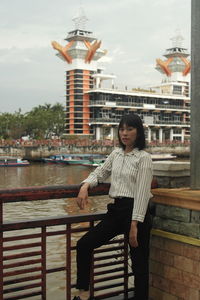 Portrait of woman standing by railing against water