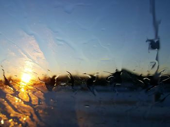 Close-up of wet car window against sky during sunset