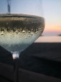 Close-up of beer glass against sky during sunset