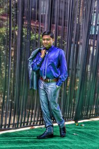 Full length of young man standing by curtains