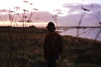 Man standing on field against sky during sunset