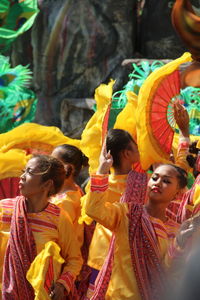 Women wearing yellow traditional clothing while dancing outdoors