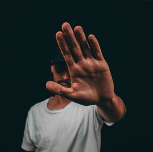Midsection of man gesturing against black background