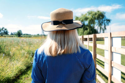 Rear view of woman wearing hat standing on field