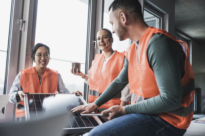 Engineers wearing reflective clothing with solar panel at office