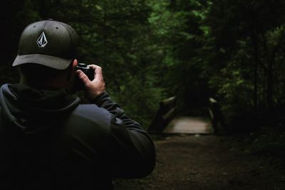 Midsection of man photographing against trees