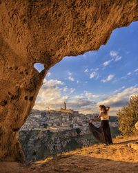 Woman standing on rock against sky