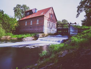 Houses by canal against sky