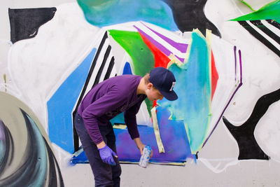 Young man painting graffiti on wall