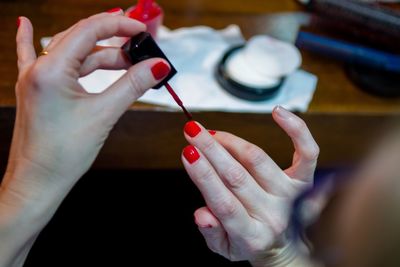 Cropped hands of woman applying red nail polish