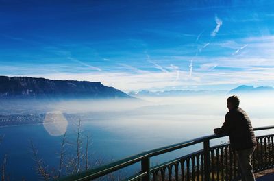 Man looking at lake against cloudy sky