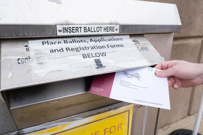 Midsection of person holding text on paper against wall