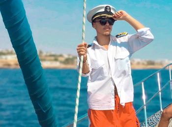 Mid adult man wearing sunglasses standing against sea