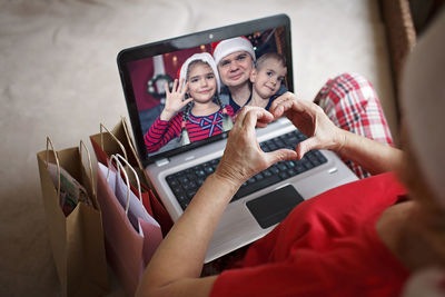 Safe online christmas celebration. senior woman in santa red hat celebrating with family virtually