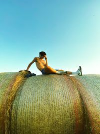 Low section of woman sitting on hay