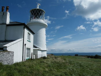 Lighthouse by sea against sky