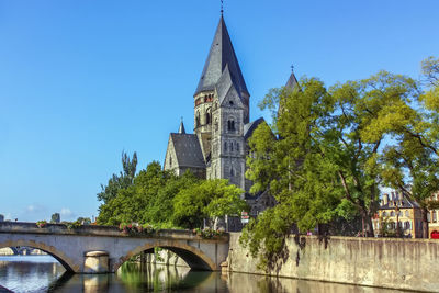 Arch bridge over river amidst buildings against clear sky