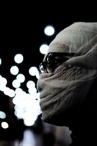 Close-up portrait of young man against illuminated lights at night