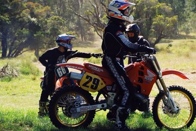 People riding motorcycle on field in forest