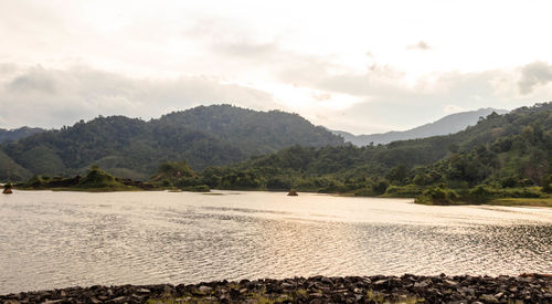 Scenic view of river by mountains against sky