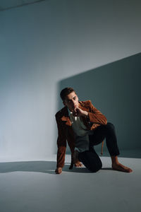 Man looking away while sitting against wall