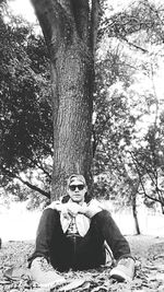Portrait of young man sitting on tree trunk