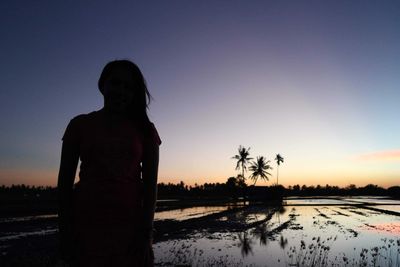 Silhouette person standing on field against sky during sunset