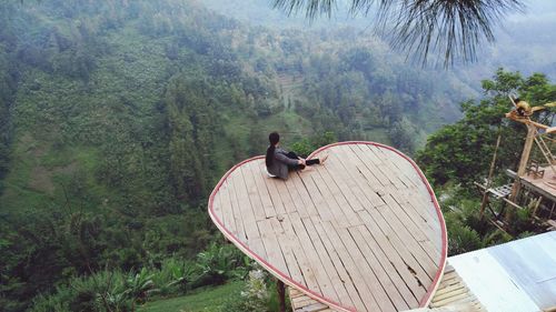 High angle view of woman sitting at observation point in forest