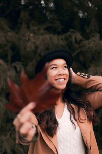 Beautiful young woman holding dry maple leaf