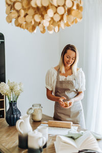 Woman preparing dough for cookies standing at domestic kitchen