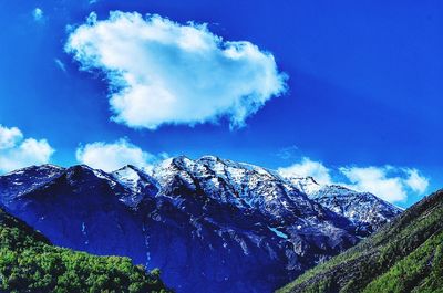 Low angle view of snowcapped mountains against blue sky