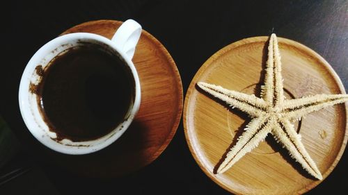 High angle view of coffee cup and dead starfish on table