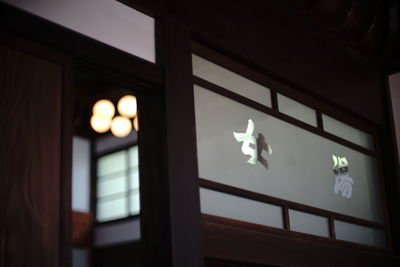 Low angle view of illuminated hanging light against building