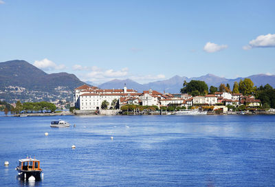 Buildings by sea against blue sky