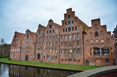 Canal by building against sky