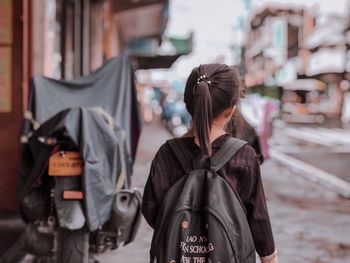 Rear view of woman walking on street in city