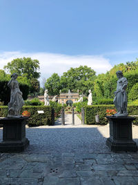 Statue against trees and plants against sky