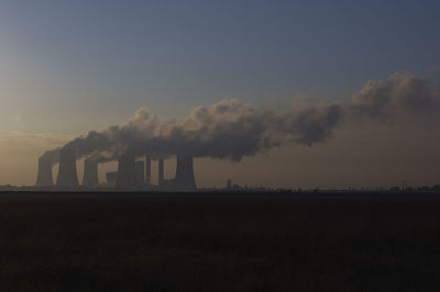 Smoke emitting from factory against sky